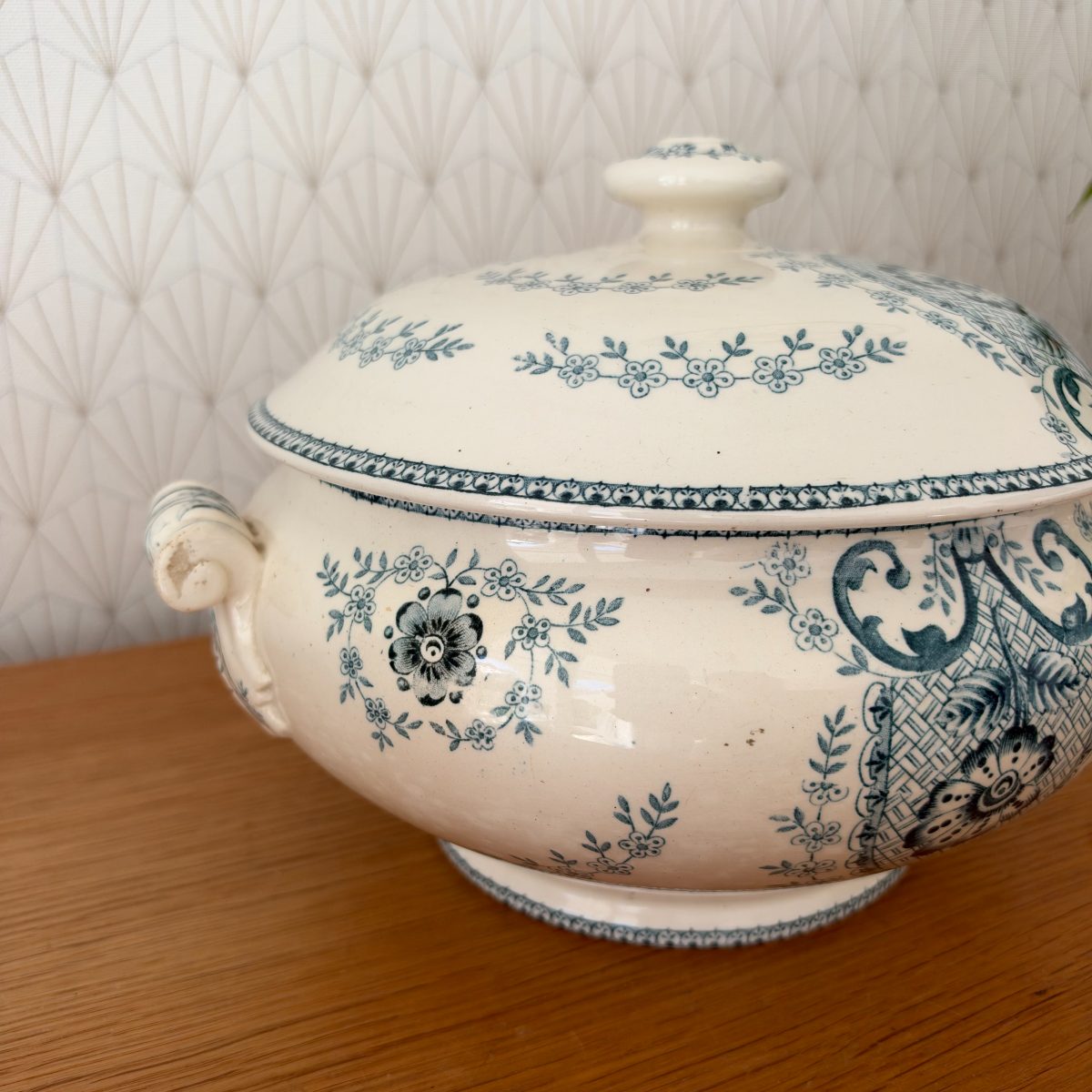 Side view of antique French blue white transferware soup tureen with lid, showing delicate floral garland border and scrollwork on cream faience.