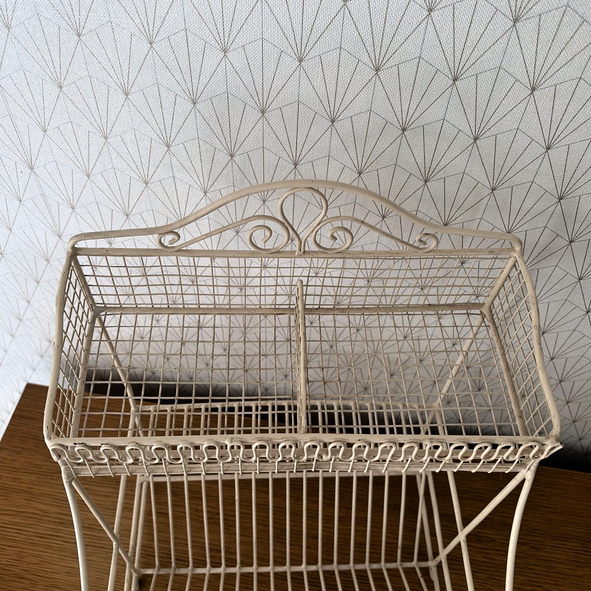 Top-down view of the upper divided wire basket of a French vintage egouttoir showing center divider and scrollwork backplate.