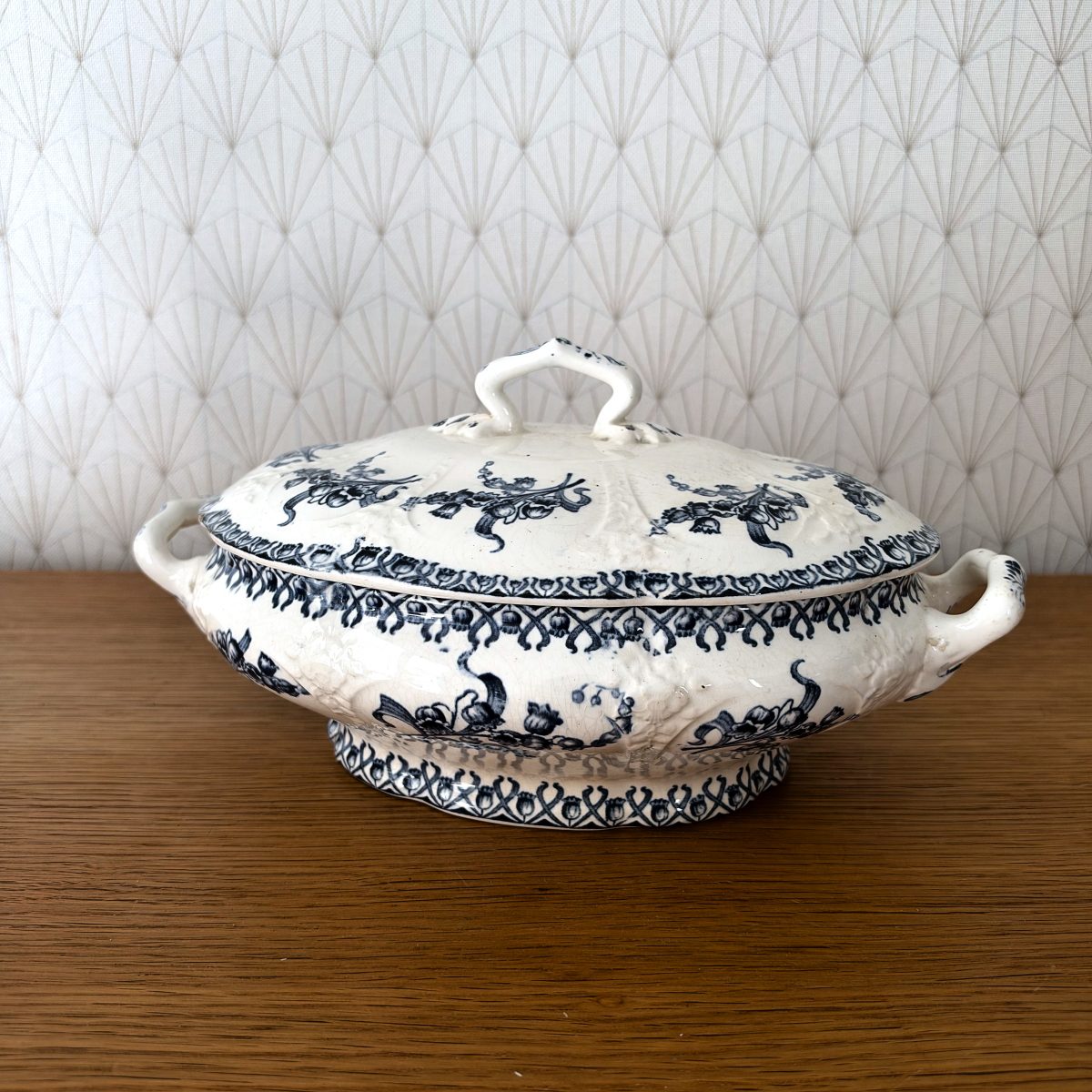 Front view of antique French blue white transferware tureen on footed base showing geometric border and floral decoration.