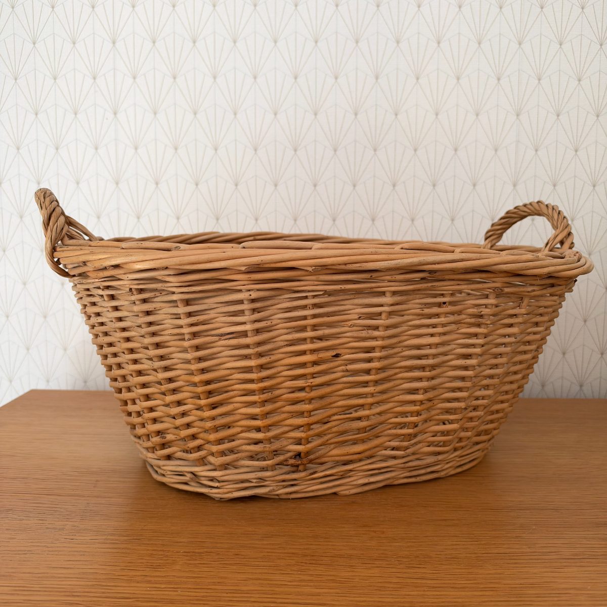 Rear view of vintage French wicker laundry basket showing consistent rattan weave and loop handles on each end.