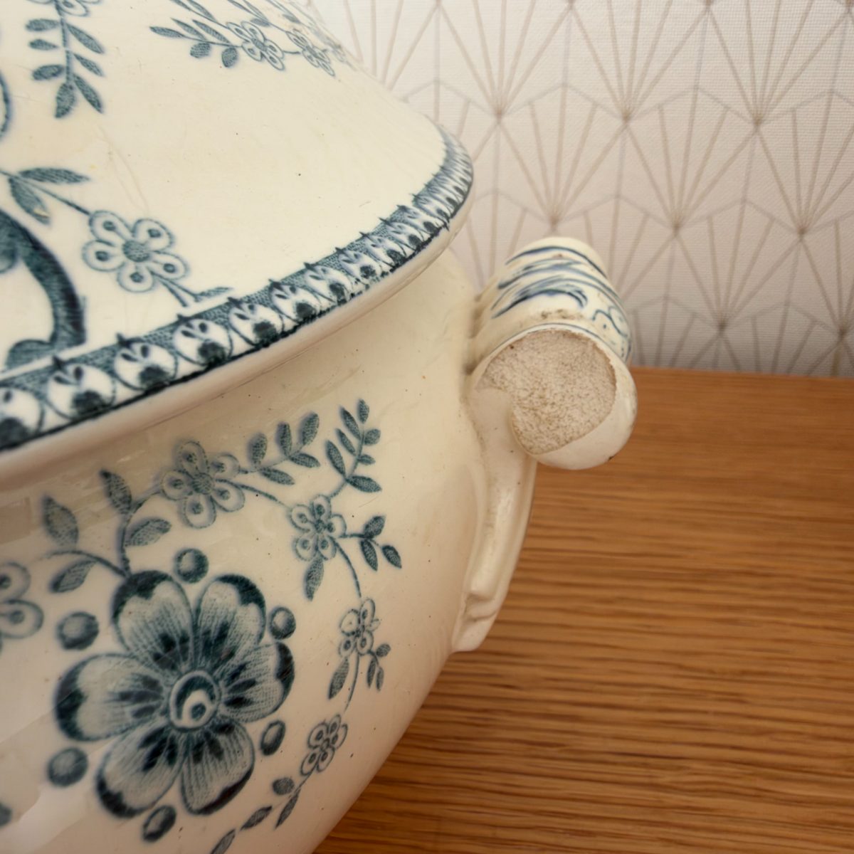 Close-up of broken handle on antique French blue white transferware soup tureen, showing chip and exposed earthenware body at break point.